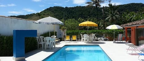 Una piscina al aire libre, sombrillas, sillones reclinables de piscina