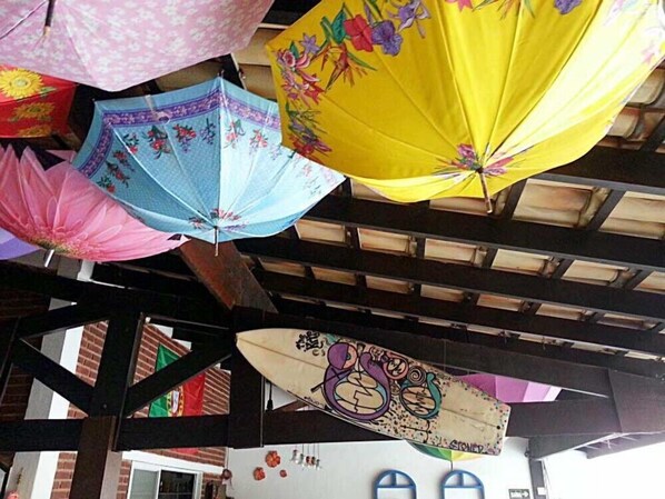 A covered outdoor area with multiple colorful umbrellas hanging from the ceiling. - Pousada Porto Paraíso (Guarujá)
