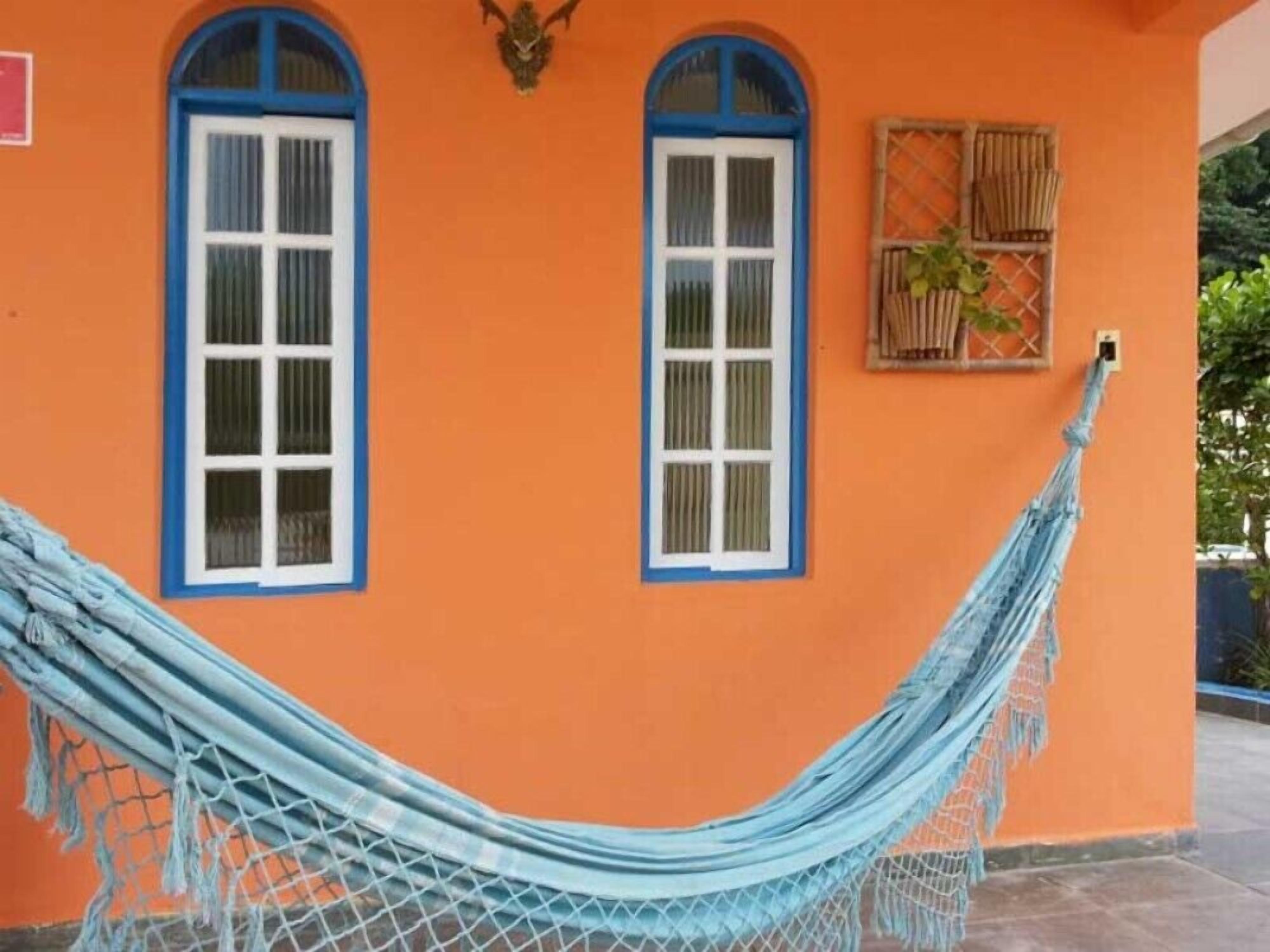 Um edifício com duas janelas, cada uma com moldura azul e vidros brancos, e um balanço suspenso entre elas.