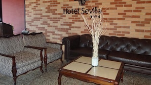 A lobby with a brick wall, a sofa, a loveseat, and a coffee table.