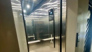 An elevator interior with reflective glass doors and a tiled floor.
