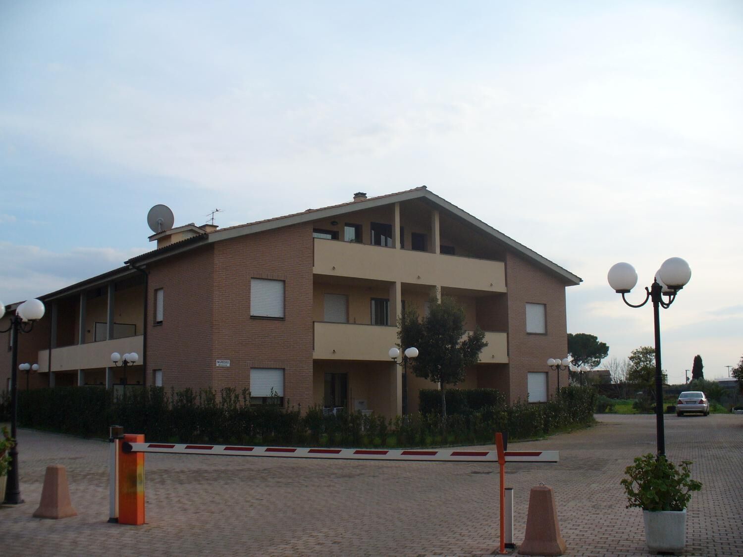 Een meerlaags gebouw met balkons, schotels en een hekwerk.