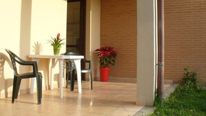 A patio area with a table and chairs, a potted plant, and a brick wall. - RTA Martin Pescatore (Grosseto)