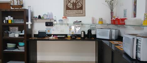 A kitchen with a coffee machine, toaster, and a clock on the wall.