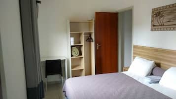 Un dormitorio con cama, un armario de madera, una mesita y una obra de arte colgada en la pared.