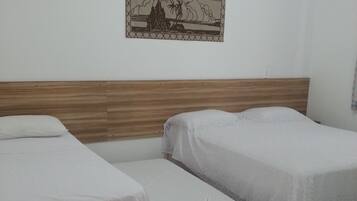 A room with two single beds, a wooden headboard, a wall-mounted picture, and a tiled floor.