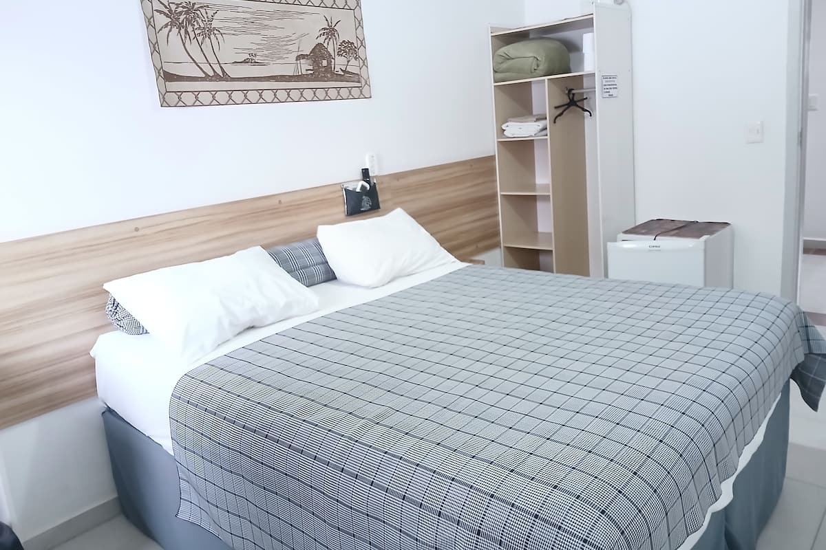 A neatly made bed with a checkered bedspread, a wooden headboard, and a wall-mounted picture.
