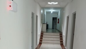 Un pasillo largo y estrecho con piso de baldosas y una escalera que sube a un nivel superior.