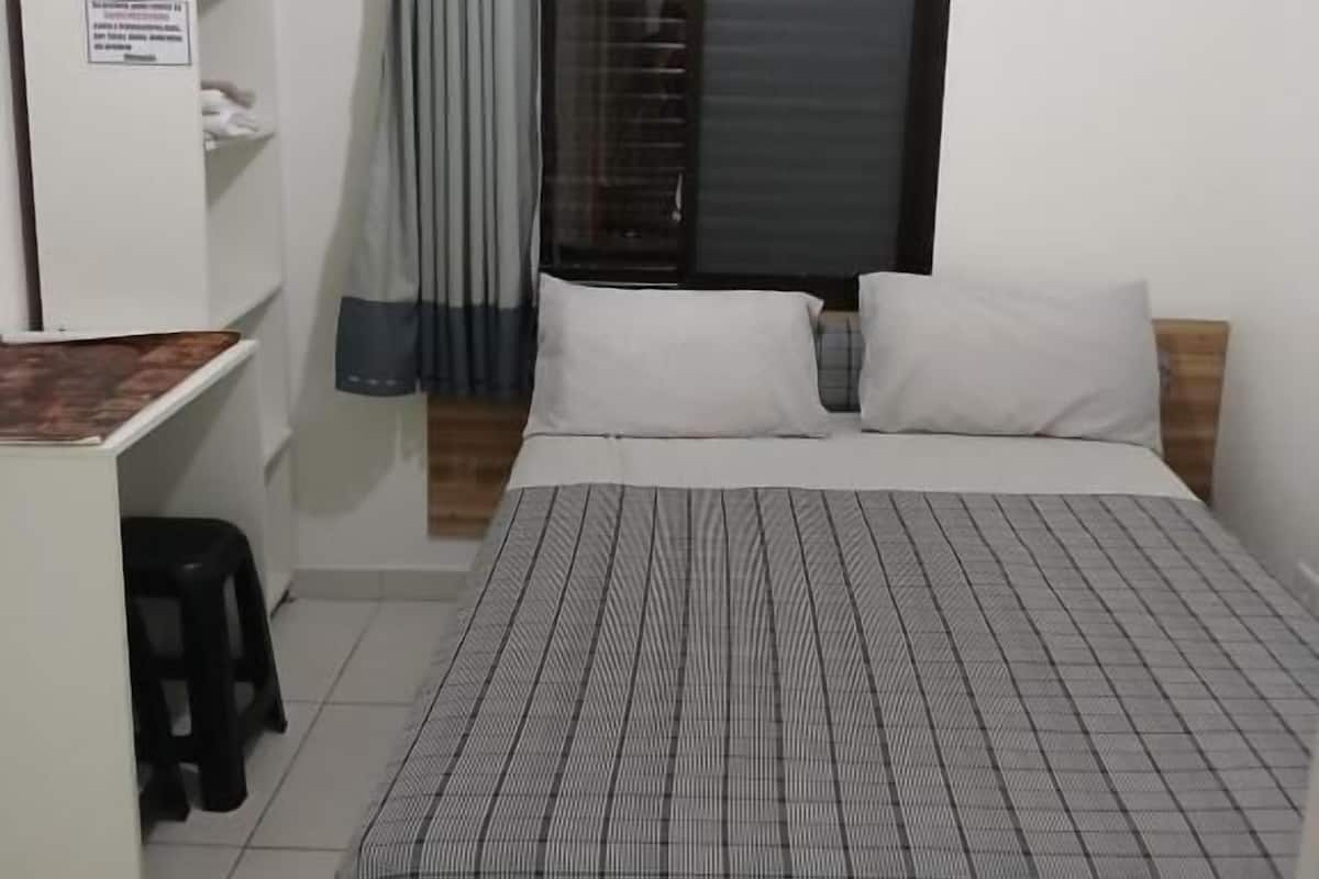 A bedroom with a bed, a desk, and a wardrobe.