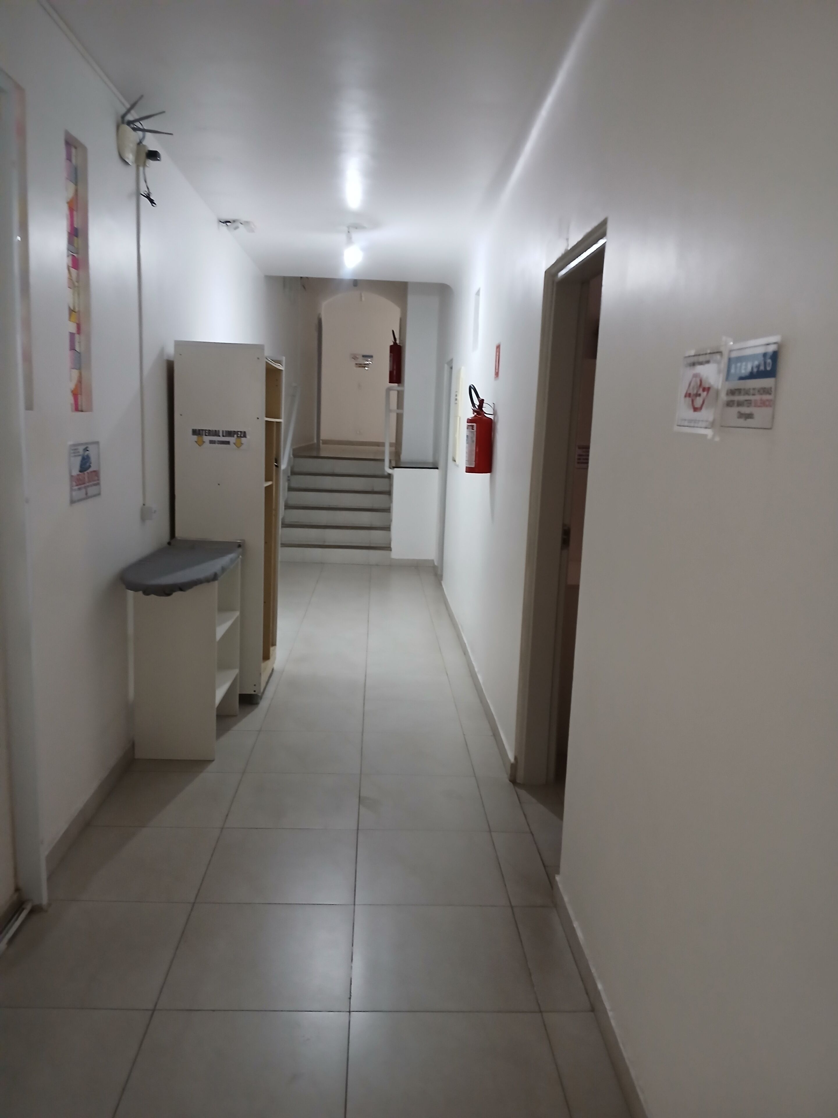 Ein Flur mit Feuerlöscher, Materialtransportsystem und einer Treppe zu einer anderen Etage.