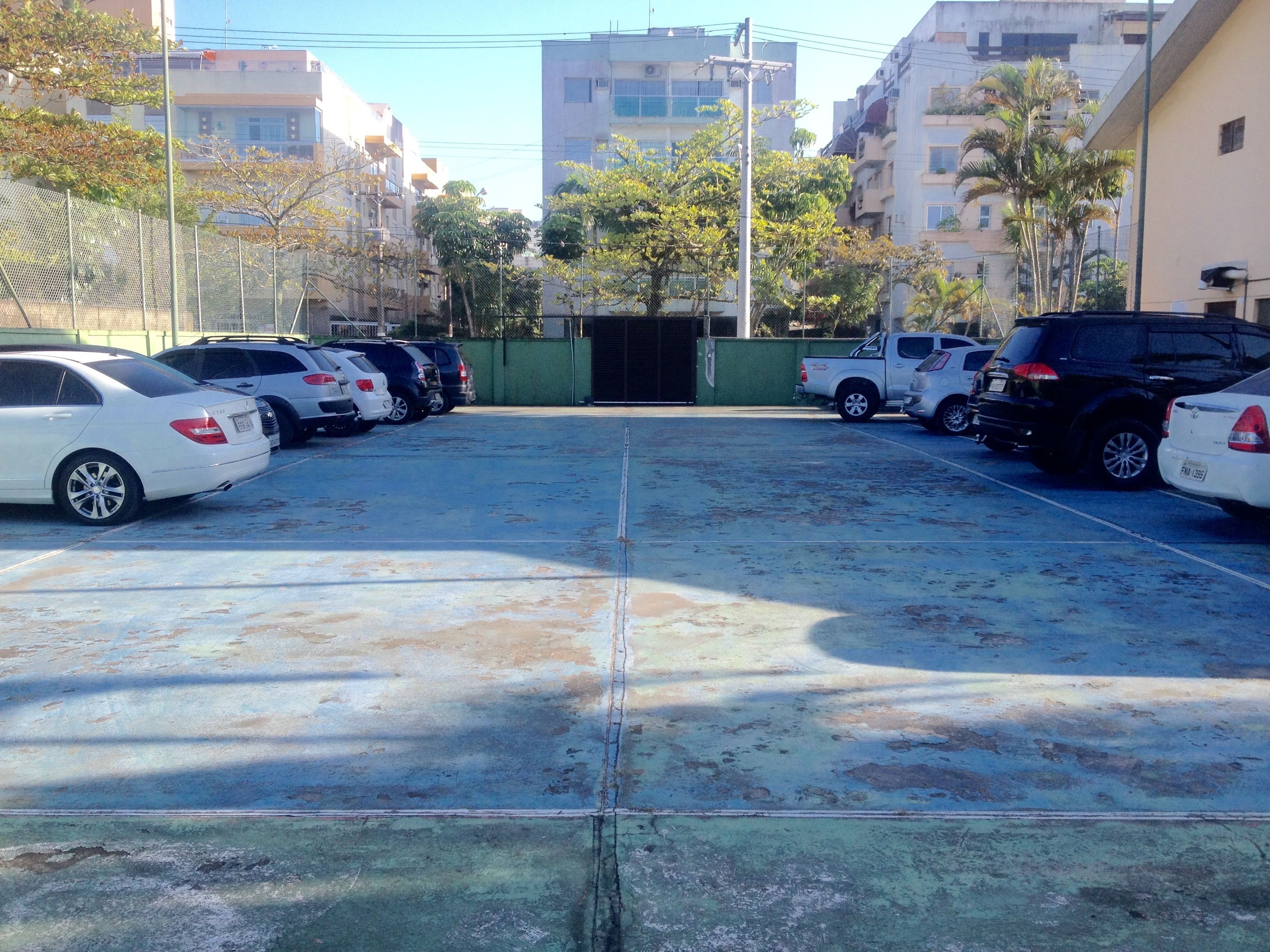 A parking lot with multiple cars and a green gate in the center.