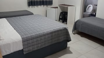 A hotel room with two beds, a TV, a desk, and a toilet.