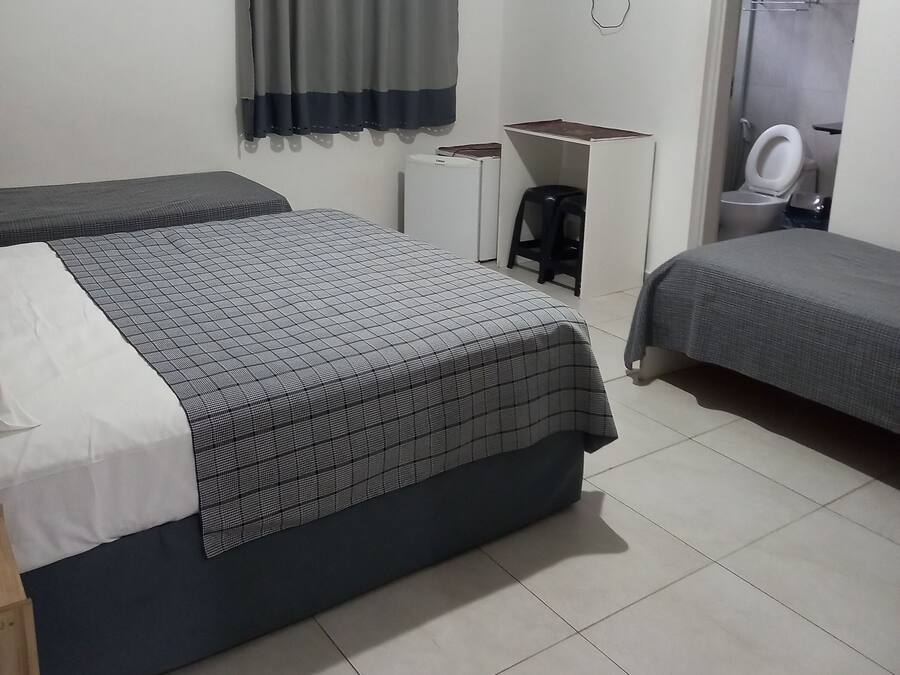 A hotel room with two beds, a TV, a desk, and a toilet.