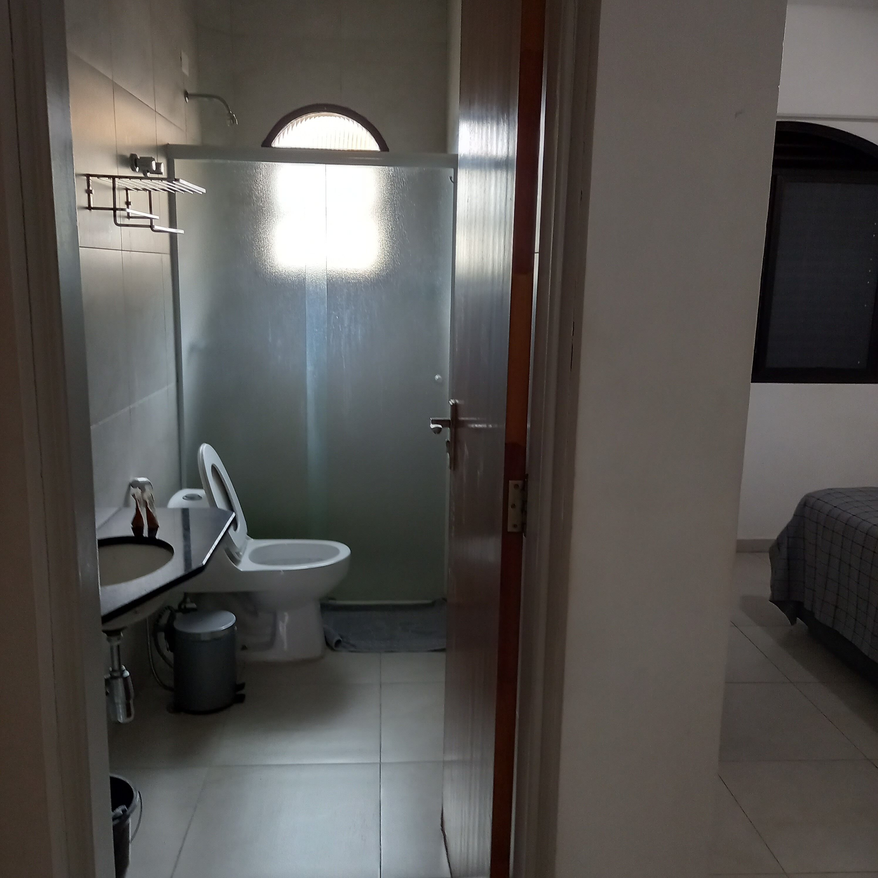 Un baño pequeño y funcional con inodoro, lavamanos y un perchero para toallas.