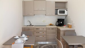 Un angolo cottura compatto con forno a microonde, macchina del caffè e un'area pranzo con due sedie e un tavolo.