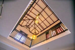 High-ceilinged interior space with a grid-like ceiling pattern and spherical light fixtures.