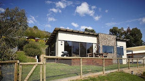 Una casa moderna su due piani, con ampie finestre, facciata in pietra e giardino recintato.