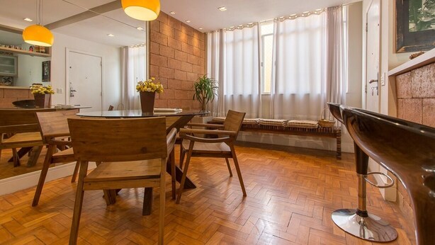 A modern dining area with wooden furniture, pendant lighting, and a brick accent wall. - Make yourself at home in the best spot in Copacabana (the beach block)! (Rio de Janeiro)