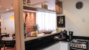 A compact kitchen with a stove, sink, and a dining area with chairs and a table. - Make yourself at home in the best spot in Copacabana (the beach block)! (Rio de Janeiro)