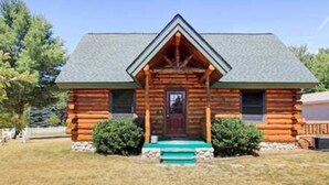 A log cabin with a gabled roof, a front porch, and a small attached shed. - A little slice of heaven (Mears)