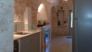 Una cucina con pareti in pietra, un frigorifero in acciaio inossidabile e un forno a incasso.