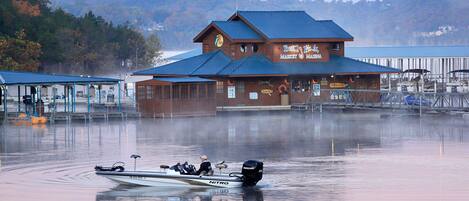 Un barco llamado 'NITRO' en una masa de agua, con un edificio al fondo identificado como 'Berry Hill Market & Marina'.
