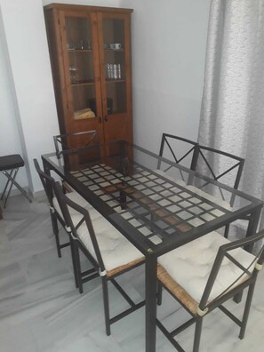 A dining area with a table and six chairs, a cabinet with glass doors, and a tiled floor.