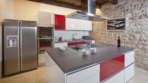 A modern kitchen with a stainless steel refrigerator, a central island with a sink, and a stone wall. - Villa Poropati, Groznjan - Luxury Countryside Estate up to 19 persons
80m2 pool  (Groznjan)