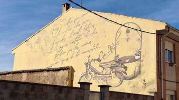 Un edificio con un mural de una bicicleta y texto escrito a mano.