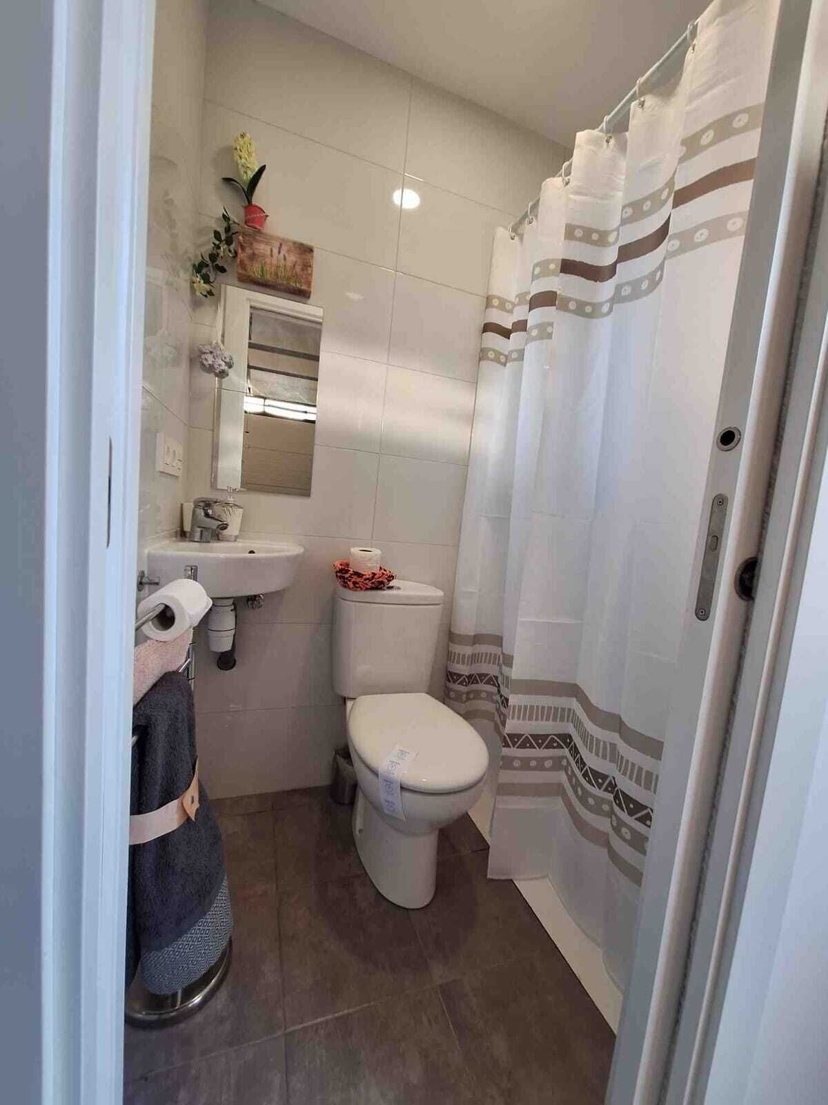 A compact bathroom with a toilet, sink, and shower curtain.