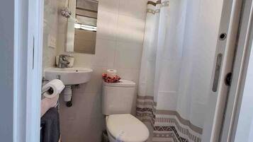 A compact bathroom with a toilet, sink, and shower curtain.