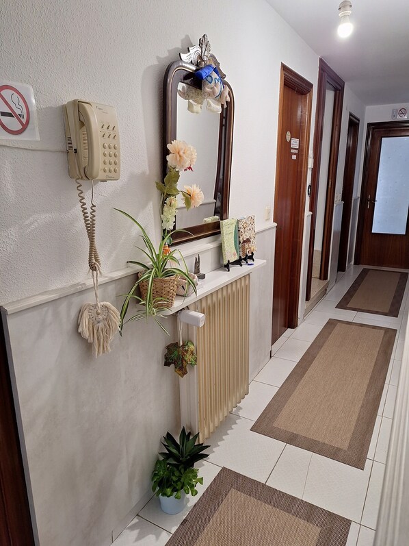 En gang med telefon, spejl, pyntede planter og en radiator.