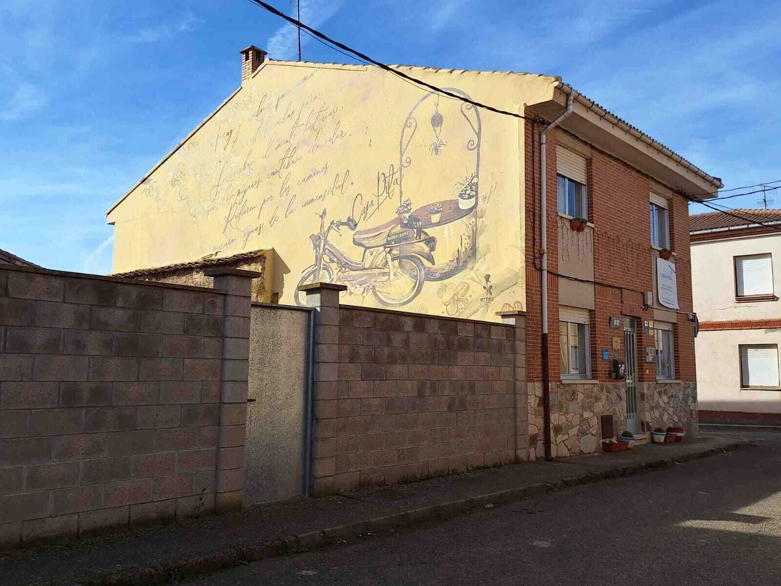 A building with a mural of a bicycle and handwritten text on its facade.