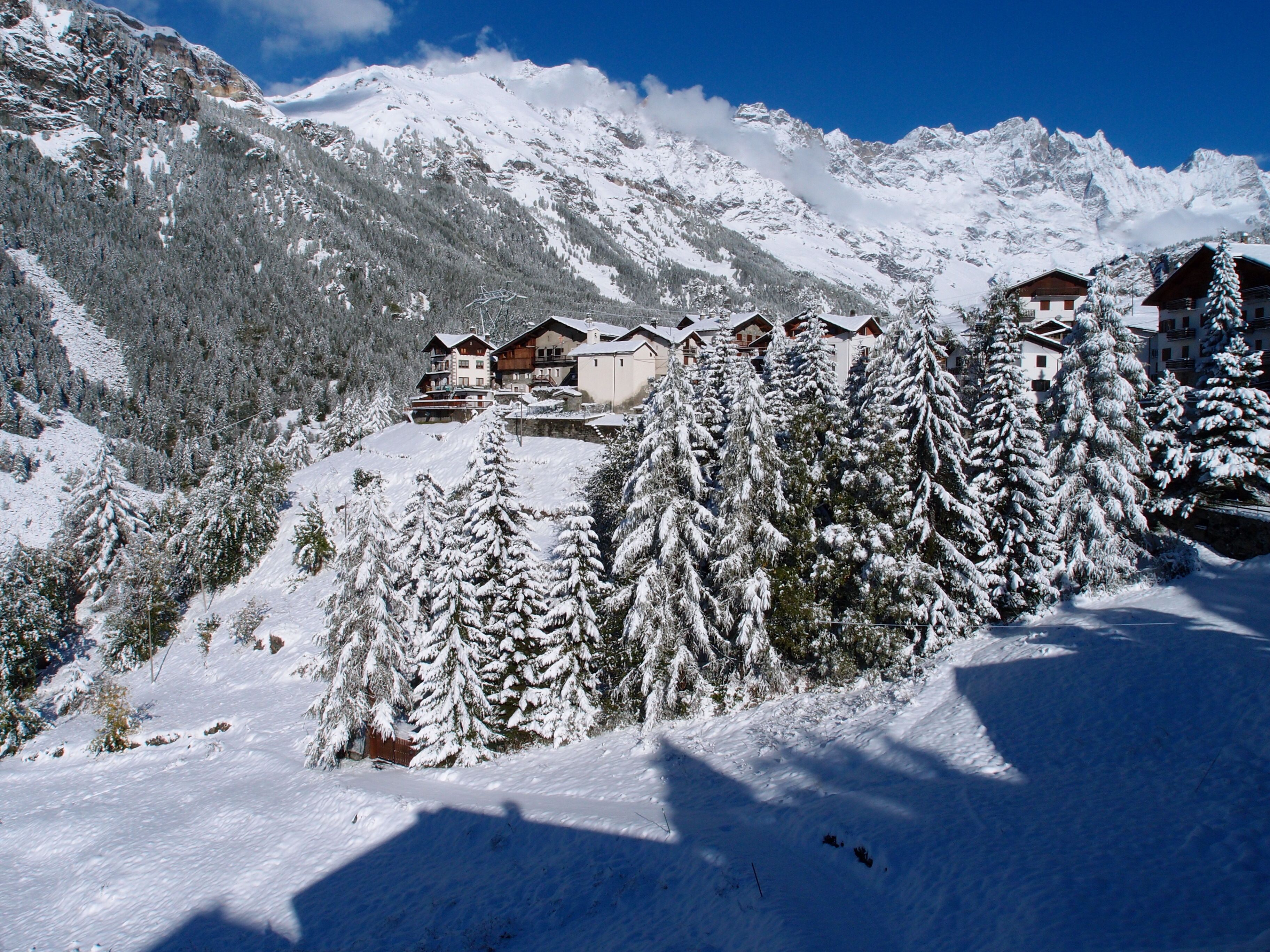 A snow-covered mountain with a row of wooden chalets.