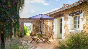 Un edificio de piedra con patio, asientos al aire libre y vistas al campo.