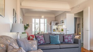 A modern living room with a grey sofa, patterned cushions, and a wooden floor.