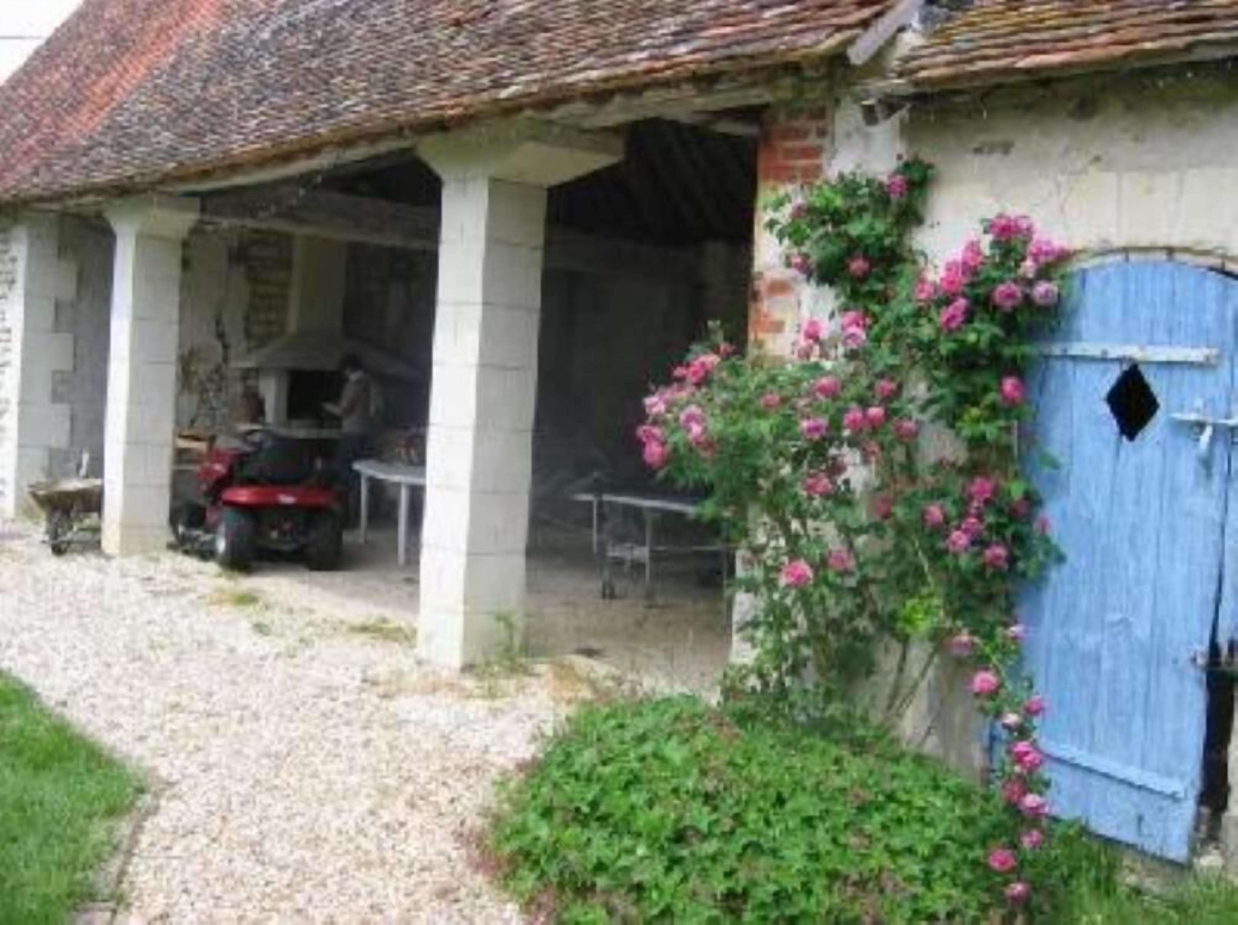 A rustic building with a thatched roof, a covered porch, and a blue door.