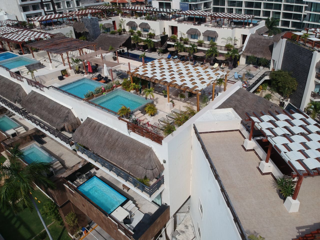 A resort with multiple swimming pools, outdoor seating areas, and thatched-roof structures.