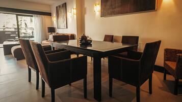 A modern dining area with a rectangular table surrounded by six chairs, a sofa, and a dining table with a decorative bowl.