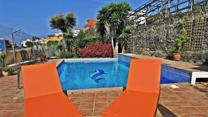 Una piscina con dos sillones anaranjados y un estampado decorativo de peces.