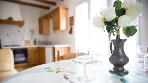 Una mesa de comedor con mantel floreado, un jarrón con flores blancas y copas de vino vacías.