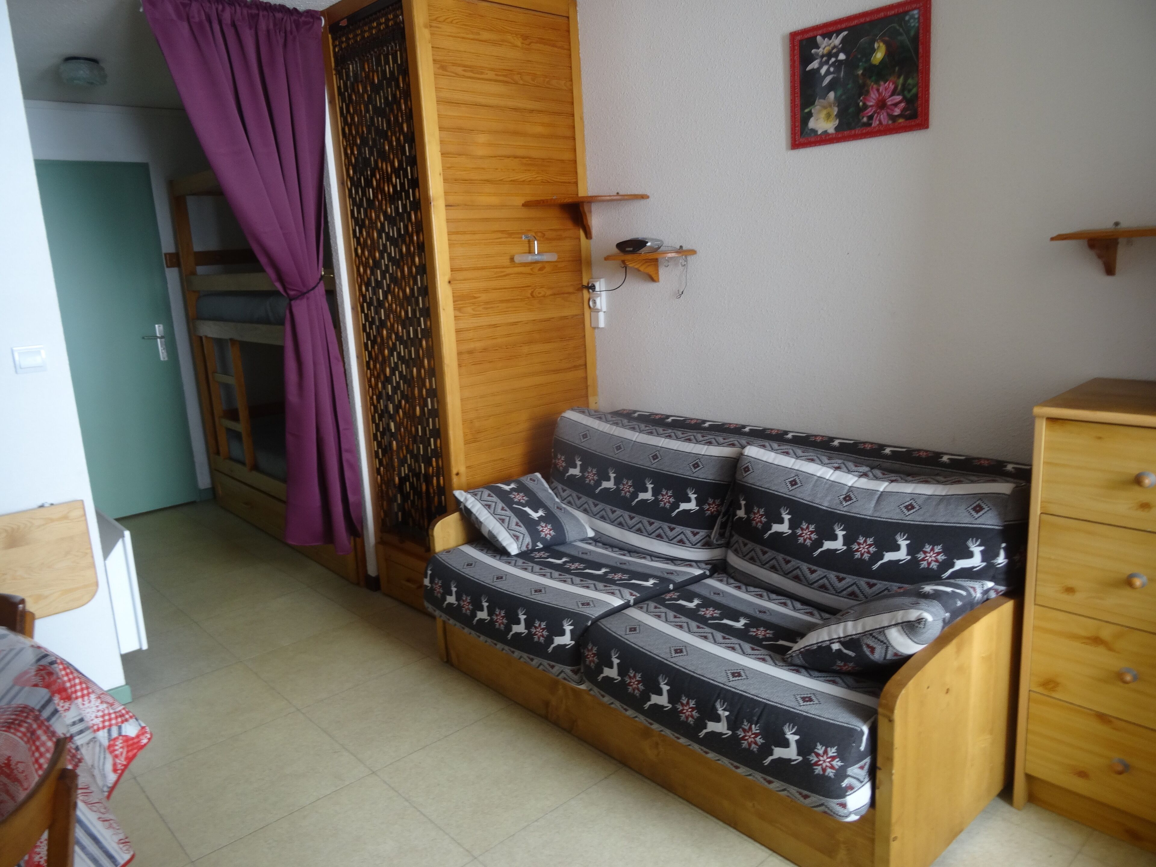 Una habitación pequeña y acogedora con un sofá y un armario de madera, además de una mesita.