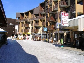 A multi-story building with balconies, a pizza restaurant, and a library. - Apartment Les Menuires - Reberty (the slopes) - Ski Soleil (Les Belleville)