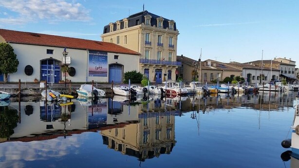 En lysthavn med både i havnen, bygninger med balkoner og en klar himmel.