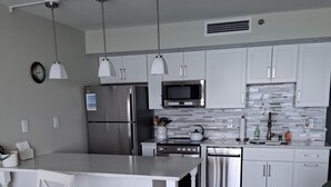 Una cocina moderna con armarios blancos, electrodomésticos de acero inoxidable e iluminación colgante.