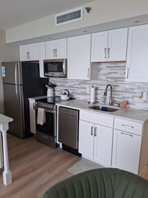 A modern kitchen with white cabinets, stainless steel appliances, a microwave, and a sink.