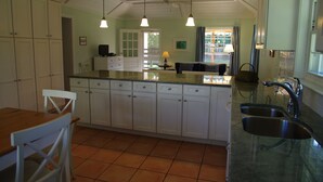 A kitchen with white cabinets, a wooden dining table, and a large window. - Tranquil Garden Setting, Private Waterfront - Sleeps 6, Twizy charger. (Somerset Village)