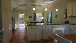 A kitchen with white cabinets, a wooden dining table, and pendant lights. - Tranquil Garden Setting, Private Waterfront - Sleeps 6, Twizy charger. (Somerset Village)