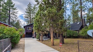 A residential area with a house featuring a garage, a small porch, and a satellite dish. - Family cabin: Hot tub, firepit, game room, fenced, BBQ, movie lineup (Big Bear)