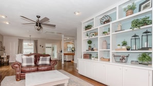 A living room with a brown leather sofa, a white coffee table, and a white cabinet with shelves. - Oak Knob Equestrian Home (Campobello)